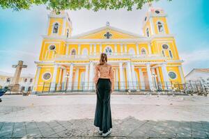 posteriore Visualizza di un' turista donna nel davanti di un' Cattedrale nel un' turista quadrato. indietro Visualizza di un' bellissimo turista nel il turista plaza di granada, Nicaragua foto
