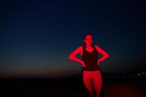 atleta scioperi un' posa nel illuminato di rosso ore notturne splendore foto