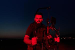 ore notturne catturare. professionale operatore video film atleti in esecuzione nel illuminato di rosso buio foto