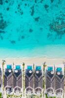 lusso spiaggia ville, sorprendente blu mare con Casa scogliera coralli al di sopra di bianca sabbioso spiaggia. Perfetto estate turismo vacanza o vacanza concetto nel Maldive o francese polinesia viaggio foto