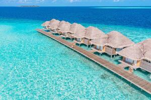 scenario paradisiaco delle maldive. paesaggio aereo tropicale, paesaggio marino con lungo molo, ville sull'acqua con splendida spiaggia di mare e laguna, natura tropicale. banner di destinazione turistica esotica, vacanze estive foto