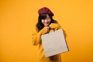 un entusiasta donna nel un' rosso berretto e giallo maglione gode sconti contro un' allegro giallo sfondo. foto