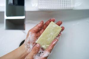 il processi di lavaggio mani con naturale sapone al di sopra di il lavello. foto
