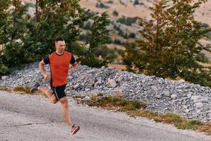 determinato atleta in esecuzione attraverso aspro montagna terreno a Alba. foto