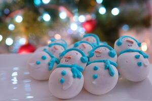 pupazzo di neve dolce macaron decorato con cappello e sciarpa con colorato luci e bokeh lampeggiante su primo piano e Natale albero su sfondo. allegro Natale e contento nuovo anno festivo concetto foto