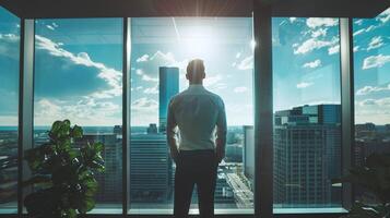 osservare il uomo d'affari in piedi nel il suo ufficio, guardando su a il città Visualizza attraverso il finestra, foto