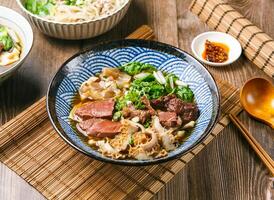 cinque stella Manzo tagliatelle con peperoncino salsa, primavera cipolla, di legno cucchiaio, e bastoncini servito nel piatto isolato su stuoia lato Visualizza di taiwanese cibo foto