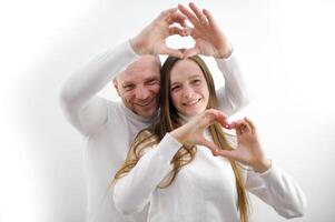 rendere un' cuore con mani uomo e donna nel amore In piedi su un' bianca sfondo leggero Abiti Due mani rendere un' cuore Sorridi ridere spazio per testo San Valentino giorno nozze tenerezza diverso età foto