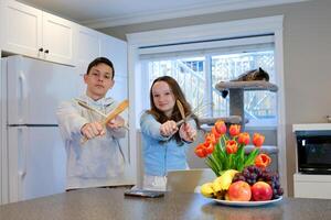 ragazzo ragazza nel cucina giocando combattente danza avendo divertimento la spesa tempo insieme Ingannare in giro mangiare Sushi solo a casa no genitori primo Data bambini giocando fratello e sorella compagne di classe amici foto