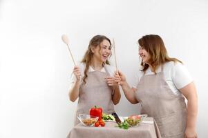 giovane contento famiglia mamma e adolescente figlia godere divertente danza nel cucina cucinando insieme. allegro adulto genitore madre avendo divertimento con adolescente adolescenziale ragazza preparazione salutare insalata a casa insieme. foto