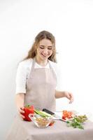 sorridente giovane donna servendo fresco insalata su piatto contento sorridente carino donna cucinando fresco salutare vegano insalata a casa con molti verdure nel cucina e provando nuovo ricetta foto