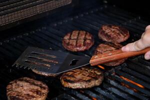 barbecue pianta basato impossibile hamburger tortini su elettrico griglia semi vicino su tiro panning al di sopra di spatola capovolto e grigliato Marrone condito hamburger tortini foto