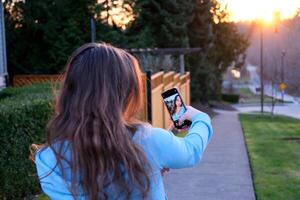 viso di bellissimo giovane ragazza guardare a Telefono girare testa Guarda in telecamera avvicinamento tenerezza modestia purezza bellezza verginità raddrizzare capelli imbarazzo sincerità nel il occhi di adolescenza adolescente foto