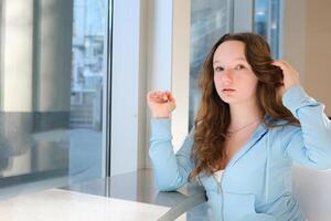 giovane donna raddrizzatura capelli in attesa per amici a scuola nel un' ristorante grande bianca ufficio formazione in linea tirocinio sviluppo modello scuola pulito bianca viso lentiggini Là è spazio per testo foto