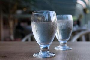 Due bicchieri di acqua su tavolo appannato bicchiere freddo bevanda puro acqua dieta Salute di legno tavolo sfocato sfondo su vuoto stomaco potabile pulito acqua primavera acqua servendo nel ristorante a inizio foto