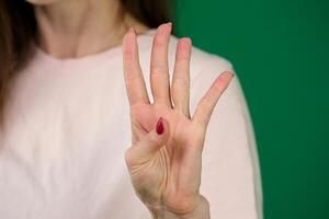 femmina mano mostrando quattro dita e palma su verde sfondo. isolato con ritaglio sentiero. foto