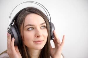 carino poco ragazza ritratto indossare grande senza fili cuffia. bella bambino ascoltando per il musica, testa tiro foto