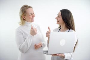 giovane ragazza medico mostrando pollice su per donna paziente donna contento anche mostrando classe lei è tutti salutare e contento aiutato medicinali su bianca sfondo bene medicina foto