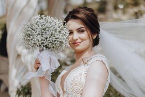 un' donna è Tenere un' mazzo di bianca fiori e indossare un' bianca nozze vestito foto