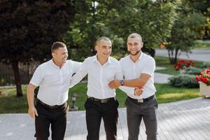 tre uomini nel bianca camicie e nero pantaloni siamo in piedi insieme foto