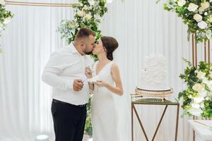 un' sposa e sposo siamo baci e mangiare un' pezzo di torta foto