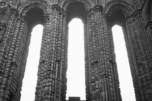 antico pietra archi con alto finestre nel nero e bianca nel tynemouth priorato e castello foto