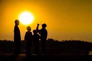 sagoma di bambino che si diverte con molti amici e gioca contro il tramonto foto