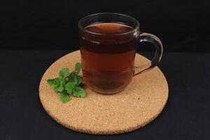 tè con menta nel bicchiere con fresco menta le foglie intorno a. fatti in casa rinfrescante bere. foto