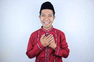 sorridente espressione di asiatico musulmano uomo accogliente Ramadan celebrazione con mani su il petto foto
