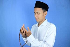 musulmano asiatico uomo Tenere preghiera perline su blu sfondo. Ramadan kareem e ied mubarak concetto. foto