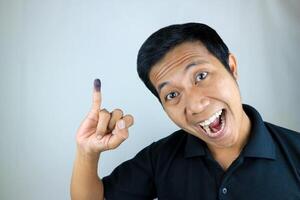 sorridente indonesiano uomo mostrando poco dito dopo voto su dell'Indonesia presidenziale elezione foto