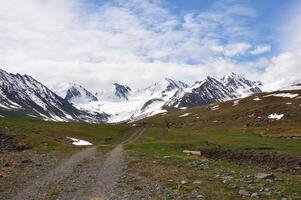 sporco strada, bianco come la neve montagne e ghiacciai, Kirghizistan. avventura viaggiare, backcountry. all'aperto, trekking, campeggio. escursionismo, valle pavimento. solitudine, ricreazione. turismo, backpacking e alpino scenario foto