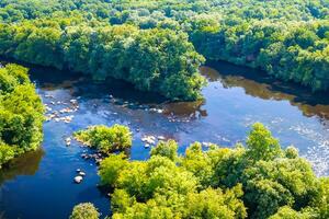 mozzafiato paesaggio un' bellissimo fiume venti attraverso affascinante aria e lussureggiante alberi, offerta un' sereno e pittoresco fuga in della natura tranquillo e verdeggiante abbraccio foto