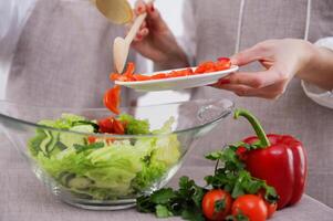 donna nel il processi di preparazione salutare cibo verdura insalata miscelazione insalata di legno cucchiaio nel cucina a casa dieta concetto. foto