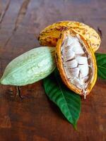metà affettato maturo giallo cacao baccello con bianca cacao seme ,tagliare nel metà fresco maturo cacao e verde crudo cacao frutta su di legno sfondo, primo piano foto
