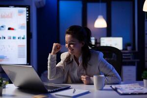 eccitato donna controllo il computer portatile per celebrare in linea vincere successo lettura grande notizia Lavorando col tempo nel inizio su ufficio. manager parlando su virtuale incontro di crescente il percentuale nel marketing foto