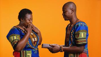 romantico uomo offerta presente con nastro e arco per il suo moglie, dando pacco regalo per celebrare sua compleanno o loro anniversario. africano americano donna ricevente dolce avvolto regalo a partire dal sua compagno. foto