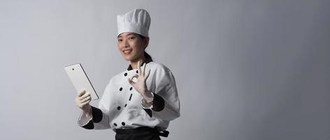 chef donna asiatica che tiene in mano uno smartphone o un tablet digitale e ha ricevuto l'ordine da online foto