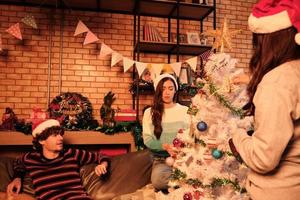 la famiglia con il cane e gli amici insieme stanno allegramente decorando l'albero di Natale bianco nel soggiorno di casa, si preparano in modo divertente e allegro per una festa per la festa del nuovo anno. foto