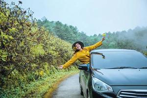 le donne asiatiche sono in vacanza. guida felicemente viaggiando verso il giardino fiorito di girasole messicano in thailandia. foto