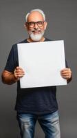 un' sorridente, maturo indiano uomo detiene un' vuoto bianca tavola nel il suo mani foto