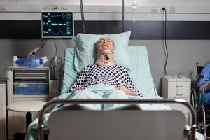anziano ricoverato in stato di incoscienza nel letto della stanza d'ospedale foto
