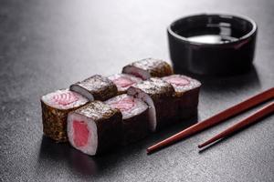 tradizionale delizioso rotolo di sushi fresco impostato su sfondo nero foto