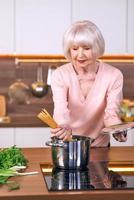 la donna allegra senior sta cucinando alla cucina moderna. cibo, abilità, concetto di stile di vita foto