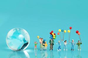 un gruppo di famiglie felici si sta divertendo e tiene in mano un palloncino con l'uso della terra come sfondo