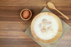 porridge di riso con polpette, uova e cucchiaio sul tavolo di legno foto