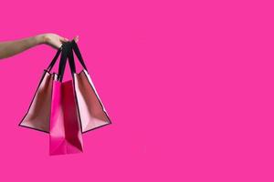 borse della spesa in mano femminile isolato su sfondo rosa con spazio di copia foto