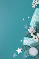 biglietto di auguri di buon natale su uno sfondo di regali, bacche e neve piatta su uno sfondo turchese, formato verticale foto