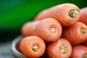 carota sul cesto, carota fresca per cucinare vegetariano su tavola di legno e sfondo verde natura.