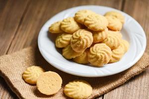 biscotti per la colazione vaniglia su piatto bianco e fondo in legno, mini biscotti biscotti. foto